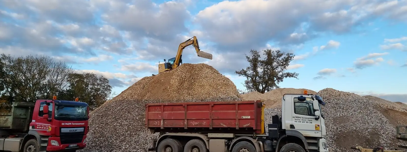 Camions-bennes De Paepe Terrassement en chargement sur une plateforme de matériaux