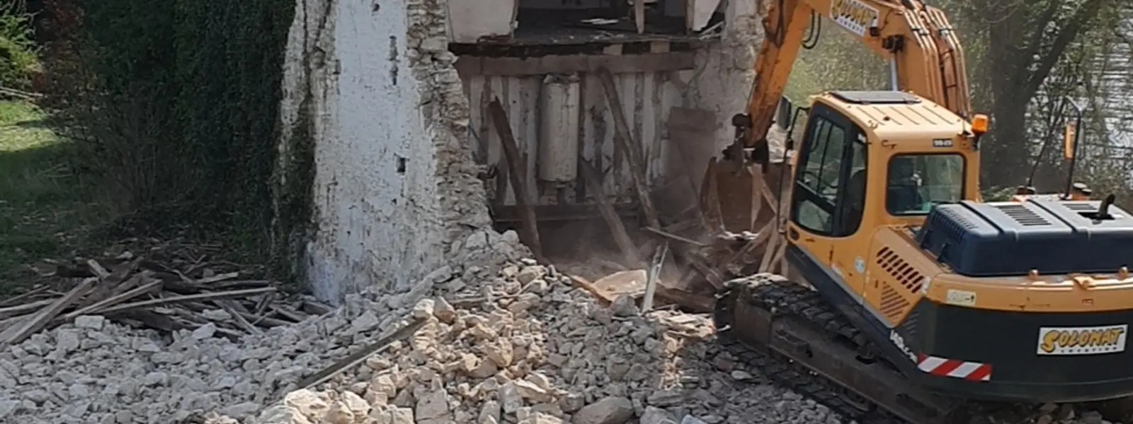Démolition d'une maison ancienne à la pelle mécanique au bord de l'eau