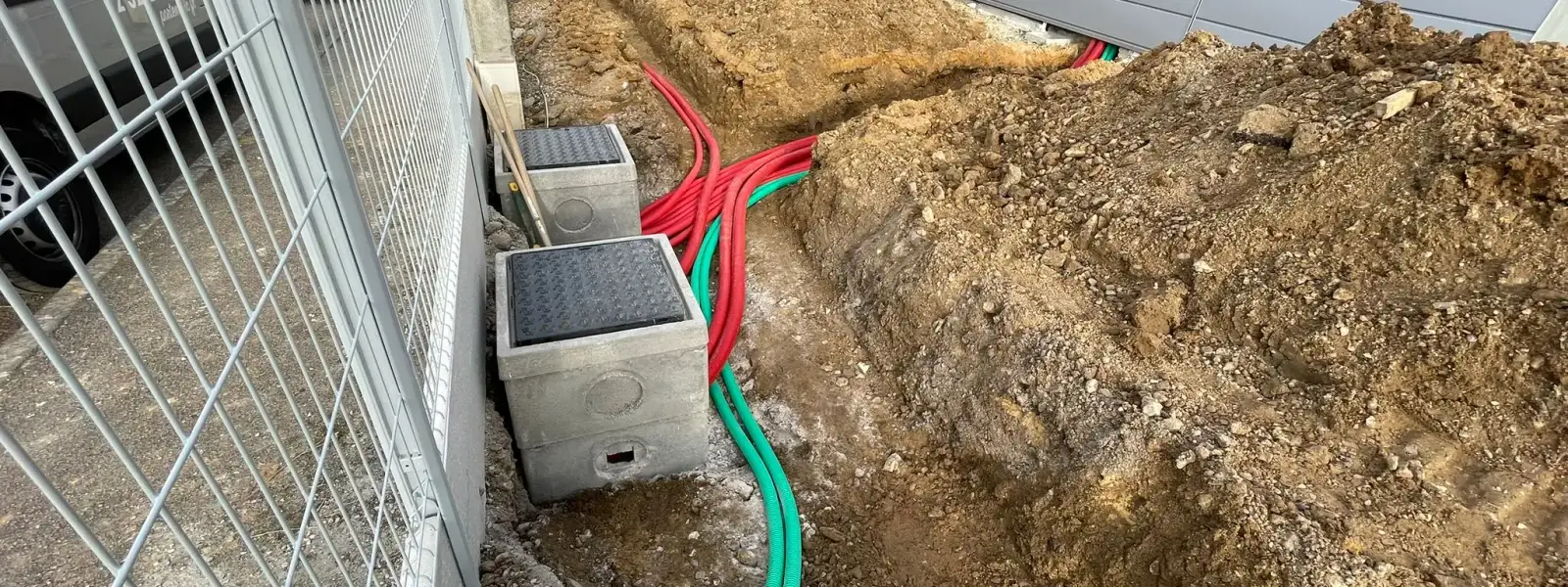 Fourreaux rouges et verts et regards béton posés en tranchée VRD