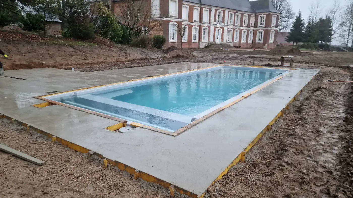 Après les travaux — piscine et sa ceinture béton dans le parc d'une demeure en briques
