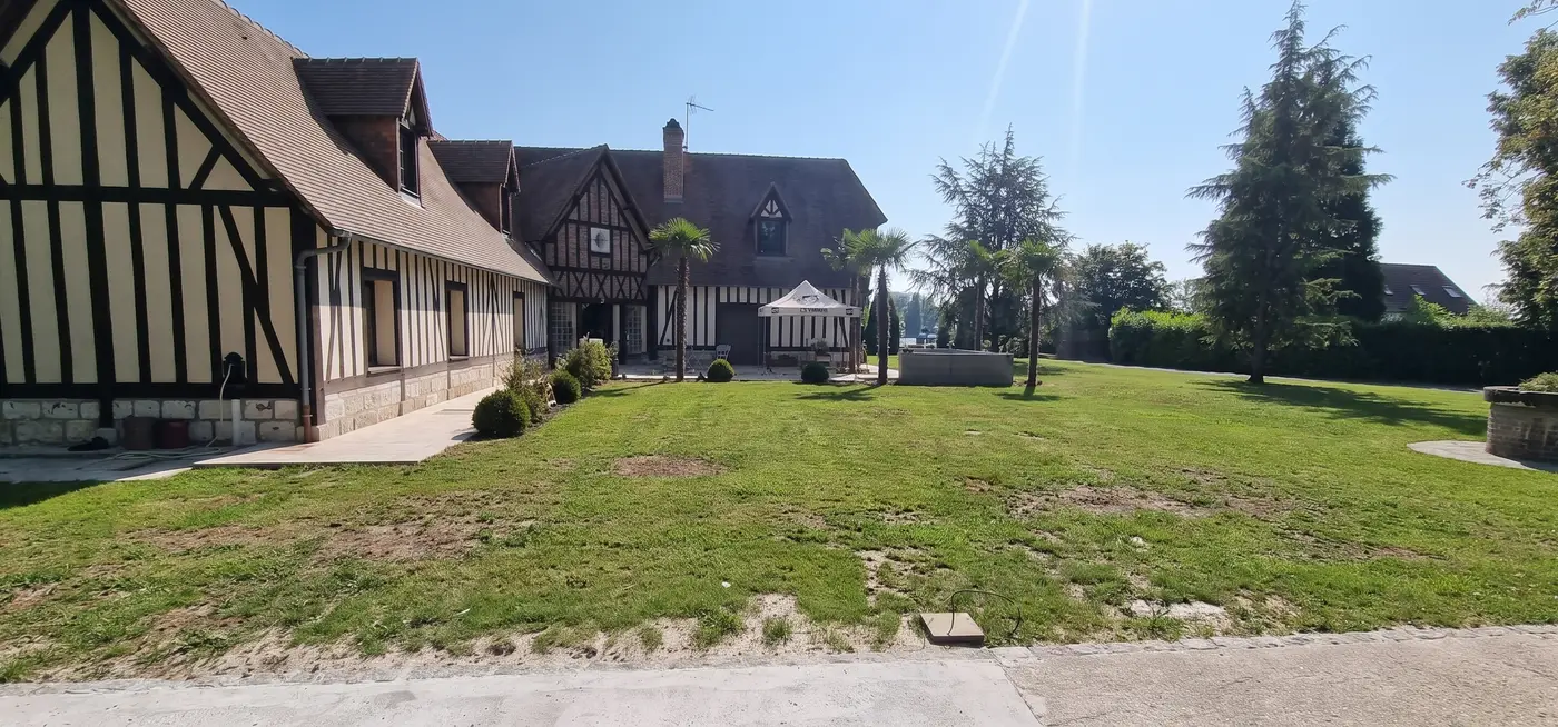 Avant les travaux — piscine et plages en pierre claire devant une maison à colombages