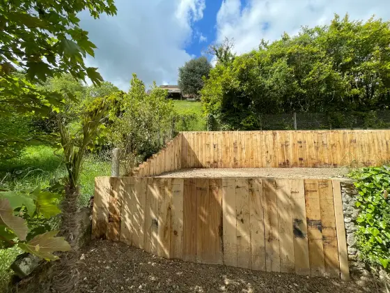 Mur de soutènement en bois dans un jardin en pente